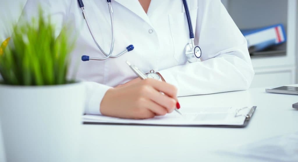Close-up view of female doctor completing forms to register with the GMC